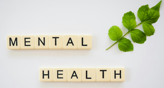 Mental health written using scrabble tiles along side a branch with leaves