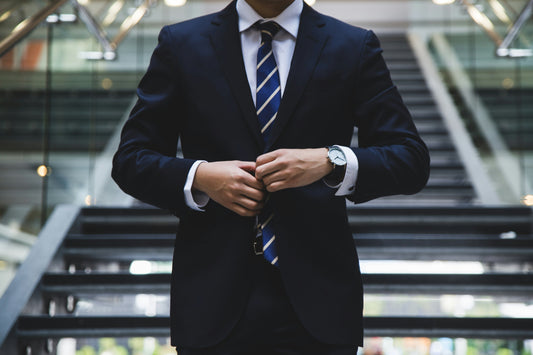 man walking with a suit on doing his blazer buttons up